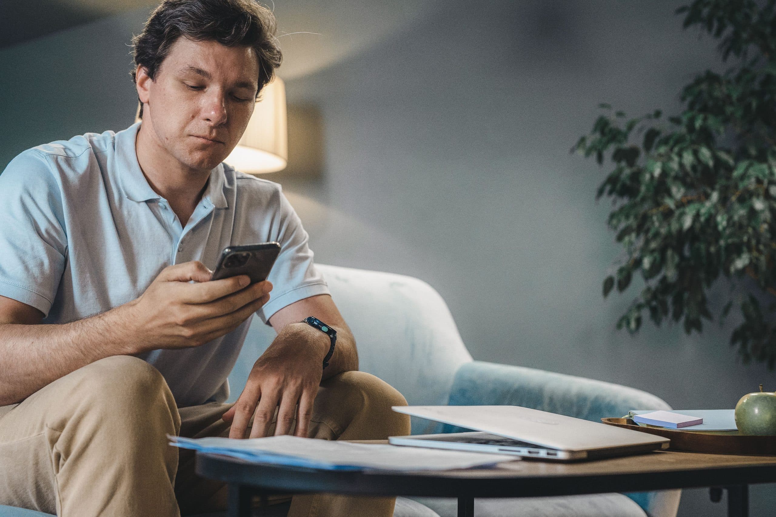 A man on a couch checking his phone at home